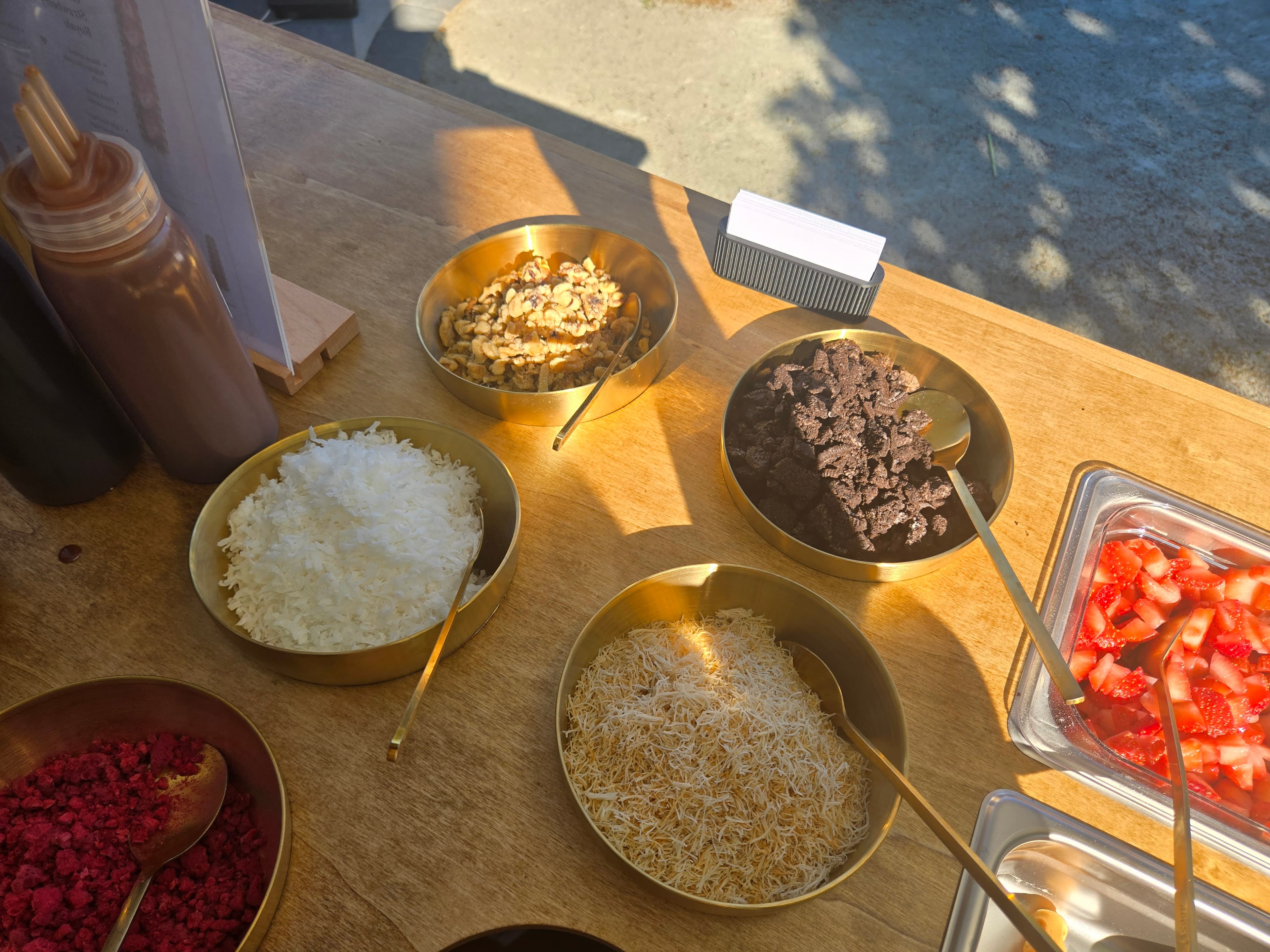 Bowls of fresh strawberries, chocolate, coconut, and walnut toppings on the Wander Waffles CO cart